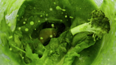 fresh vegetables adding smoothie in blender close up. top view blending veggies.