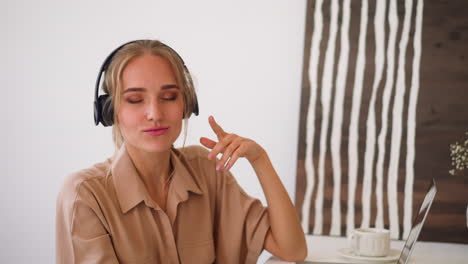 woman listens to music in headphones while working at laptop