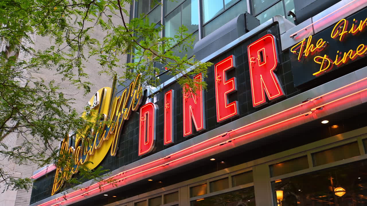 Nueva York, EE. UU., 1 de agosto de 2025: Letrero retro de un restaurante en Nueva York. Primer plano de un letrero de neón brillante de un restaurante retro rodeado de árboles y edificios en Nueva York.