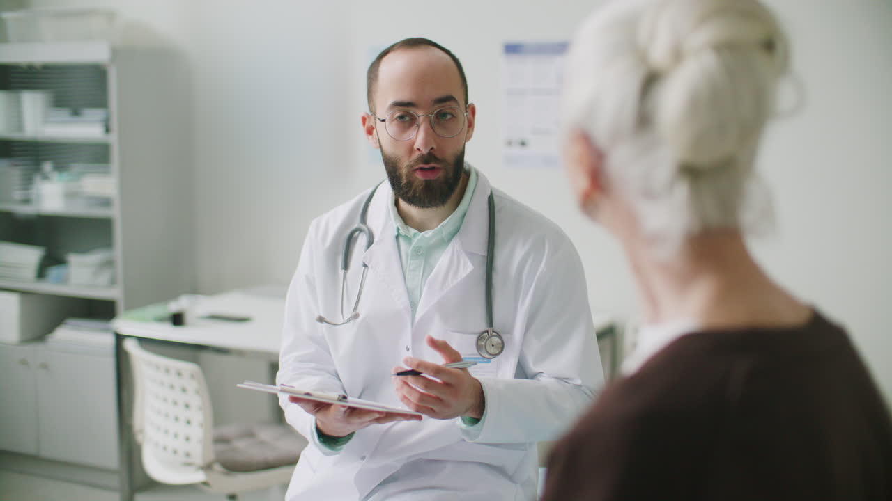 Doctor Speaking with Elderly Patient during Medical Checkup in Clinic