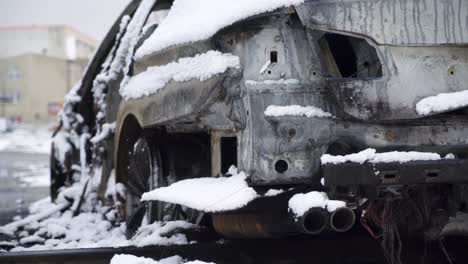 arson vandalism burnt-out car, city crime scene vehicle covered in snow