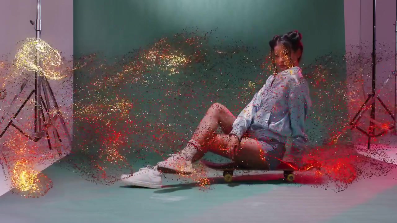Model posing on skateboard, gold sparkles entering right sweeping over subject in studio portrait