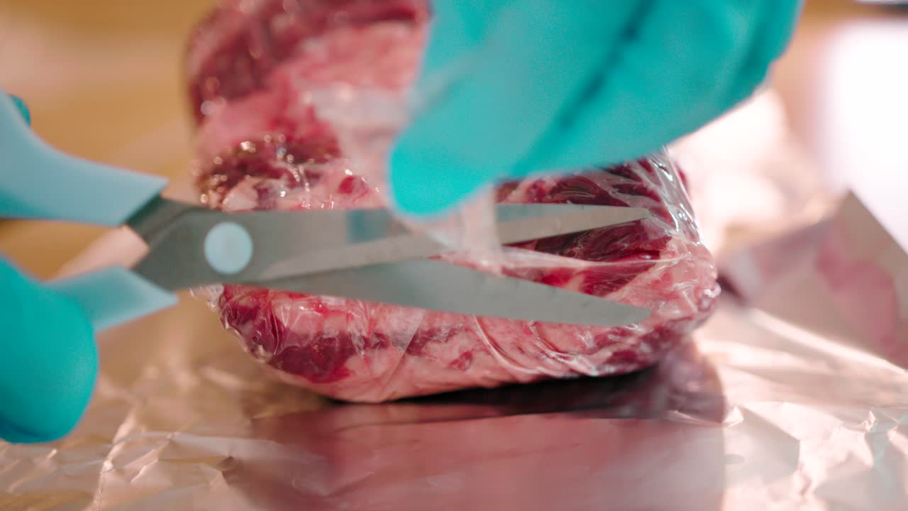 vista ravvicinata di un uomo che taglia l'involucro di polietilene imballato con un paio di forbici