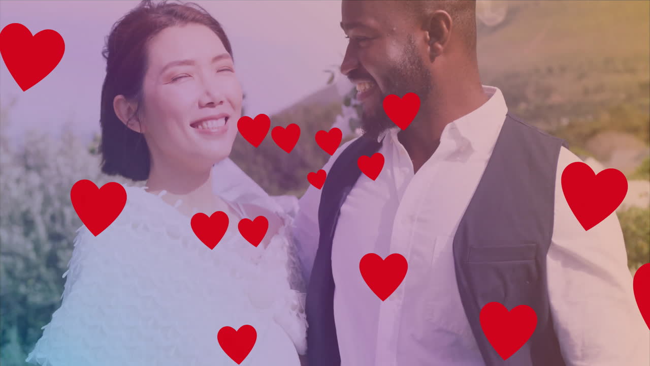 은 심장 애니메이션으로 야외에서 미소 짓는 커플이 그들 주위에 떠다니고 있습니다.