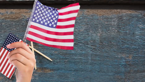 animation of person holding american flag on wooden background