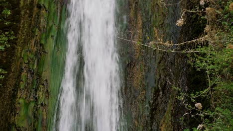 powerful stream of waterfall, mossy rocky mountain behind, static view