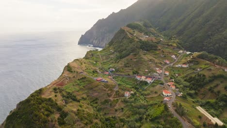 Pequeño-Pueblo-Cerca-Del-Acantilado-Y-El-Pico-En-El-Verde-Campo-De-La-Isla-De-Madeira