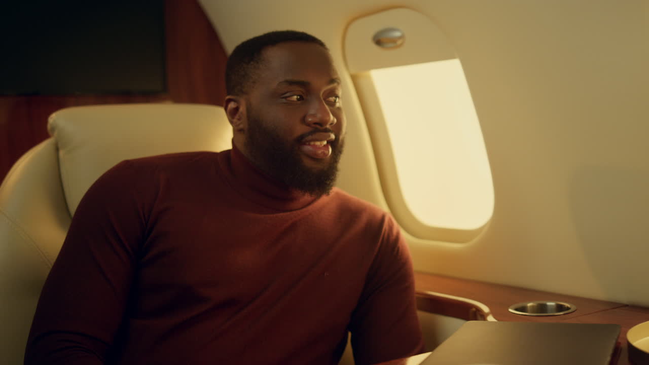 Successful african american guy traveling plane closeup. Smiling bearded man