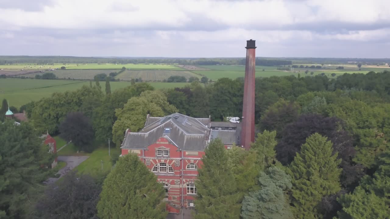 4k Drone footage panning in towards an old brick building in the middle of a forrest