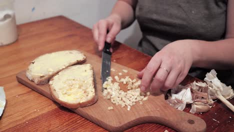 woman's hands puts garlic on a slice of bread spread with butter