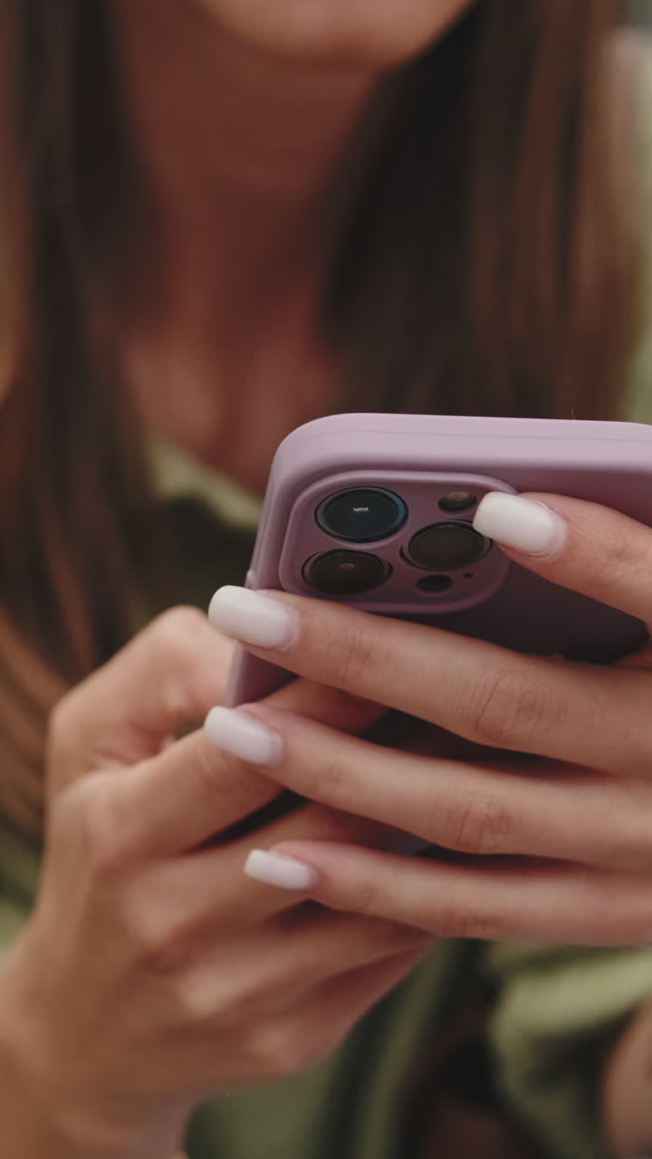 Primo piano di mani che usano uno smartphone con custodia viola