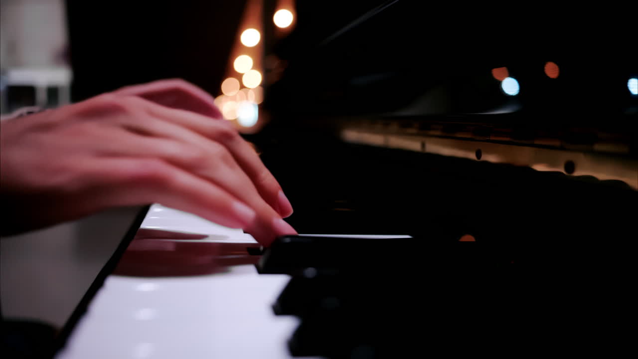 Close up of a woman's hands playing the piano with blurry lights on the background