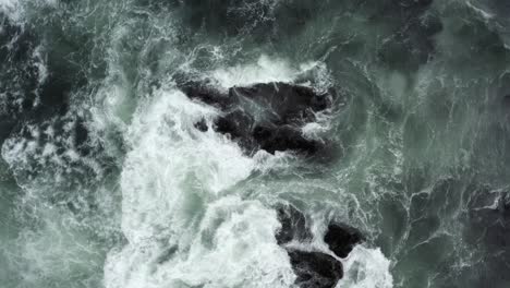 topdown view of raging waves breaks on rocks