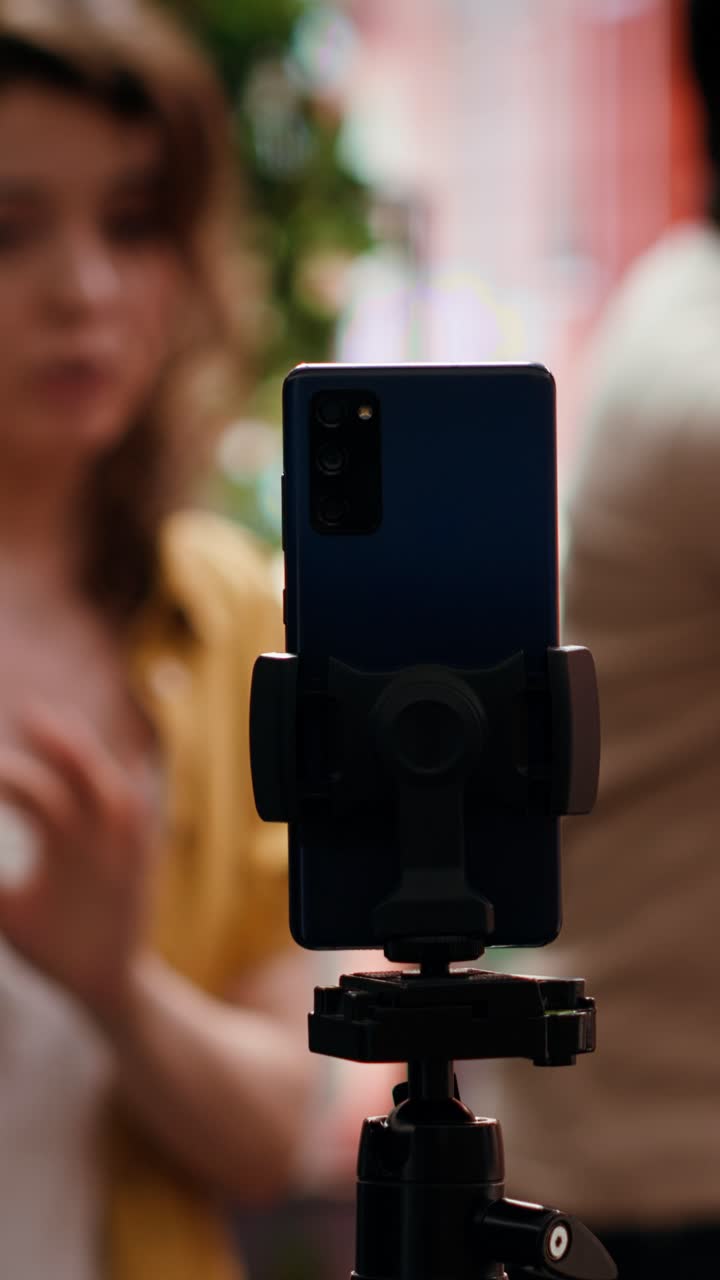 Smartphone su treppiede che riprende persone creative con sfondo sfocato.