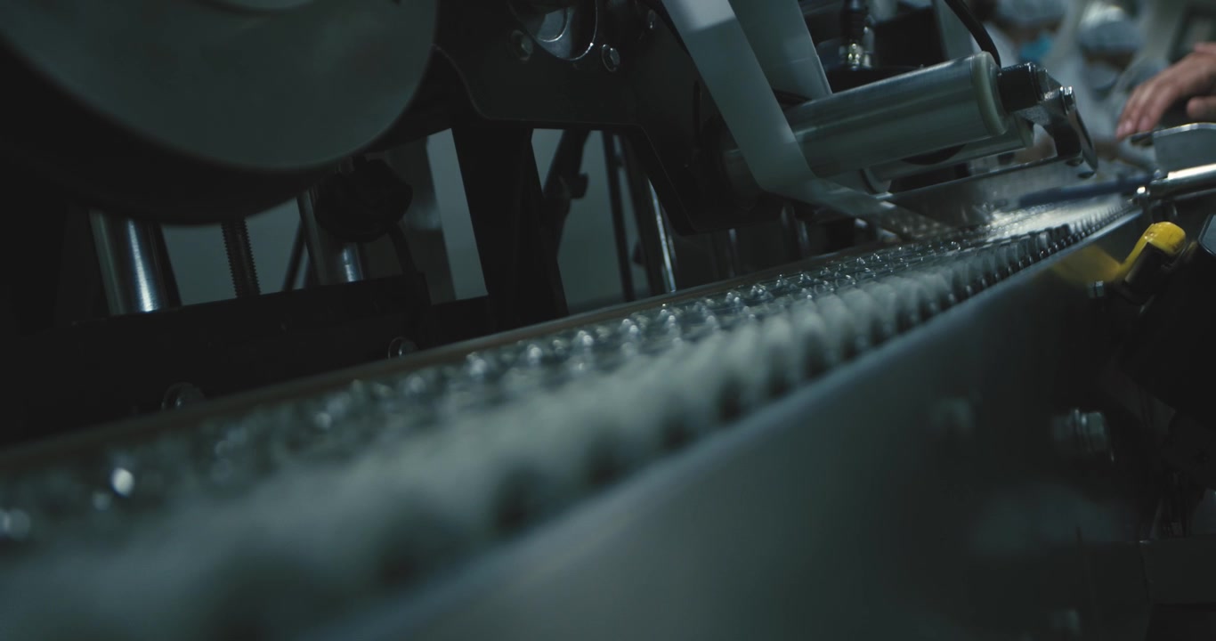 Close-up of vaccine vials moving along an automated production line in a sterile pharmaceutical manufacturing facility