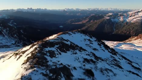 breathtaking aerial view over majestic snow-capped mountains at sunset, showcasing vast wilderness with rugged terrain and stunning peaks in the distance