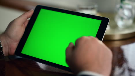 manos de primer plano usando el panel de pantalla verde. hombre rico toca la tableta digital computadora