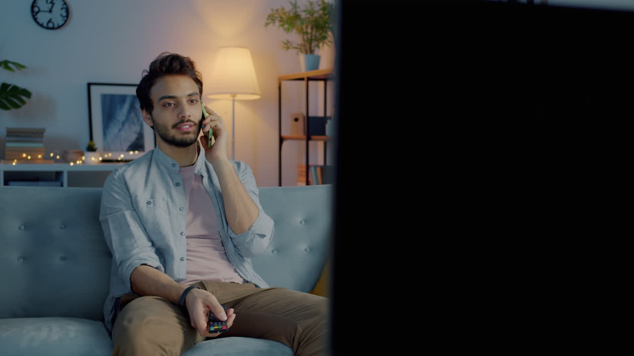 Uomo che guarda la TV e parla al telefono