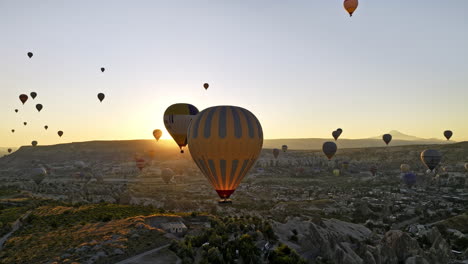 Göreme-Turquía-Aérea-V59-Paisaje-Dorado-Del-Amanecer,-Campo-De-Meseta-De-Sobrevuelo-Que-Captura-Un-Paisaje-Mágico-De-Cuento-De-Hadas-Con-Coloridos-Globos-Aerostáticos-En-Lo-Alto-Del-Cielo---Filmado-Con-Mavic-3-Cine---Julio-De-2022