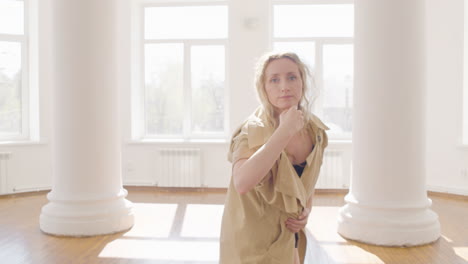 Mujer-Rubia-Enfocada-En-Gabardina-Y-Botas-Entrenando-Una-Danza-Contemporánea-En-Medio-Del-Estudio-5