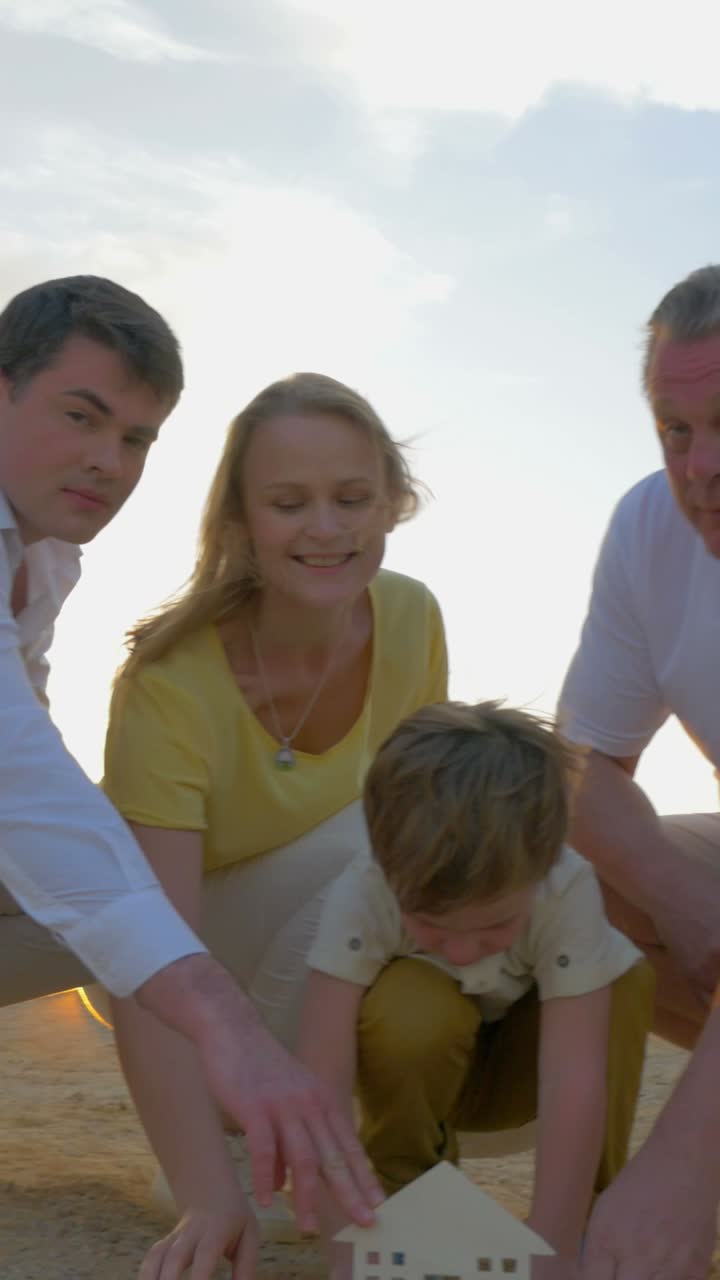 Family playing with a toy house on the sand
