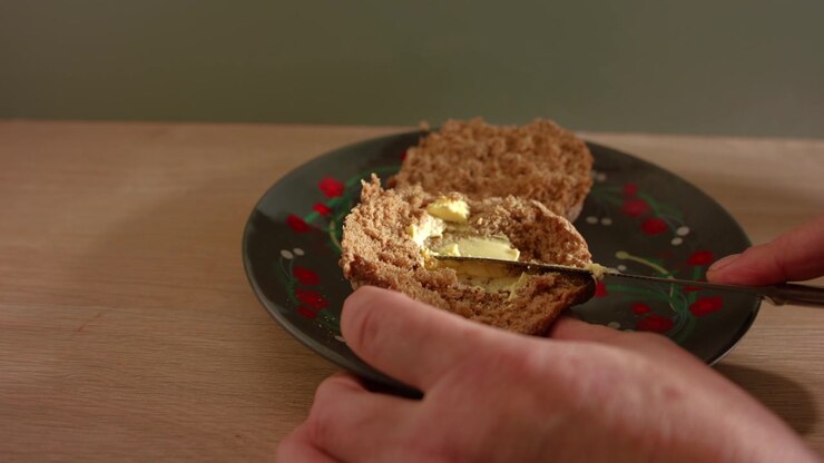 Hand buttering brown wholemeal bread for sandwich close up slow motion 4k shot selective focus