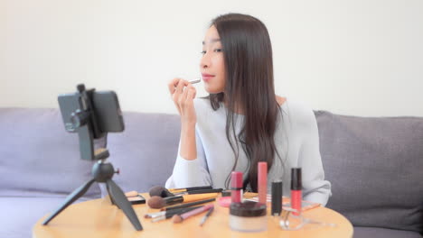 Asian-woman-makeup-blogger-recording-video-on-smartphone-reviewing-a-lipstick