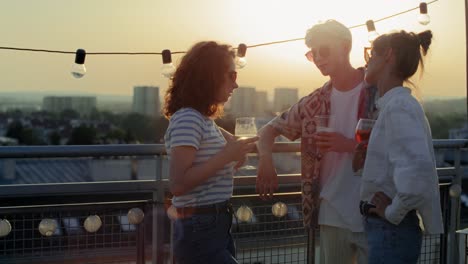 jovens amigos adultos a conversar juntos na festa durante o pôr-do-sol.