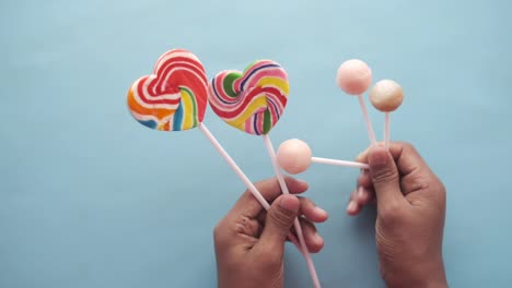 hand hold rainbow heart shape candy on color background