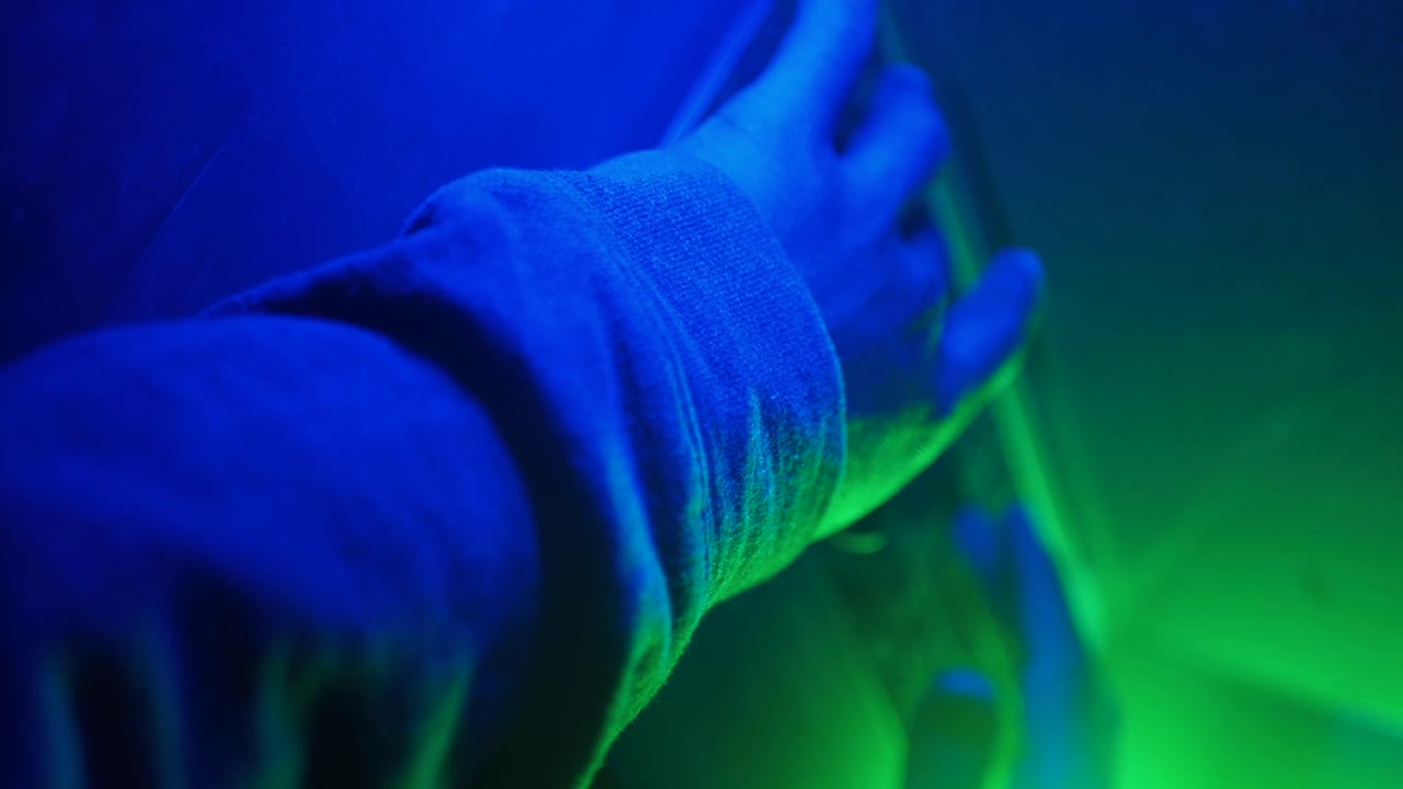 Person's Hand and Arm in Blue and Green Light