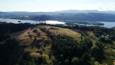 drone shot of green hills and lake windermere in sunlight, lake district, uk