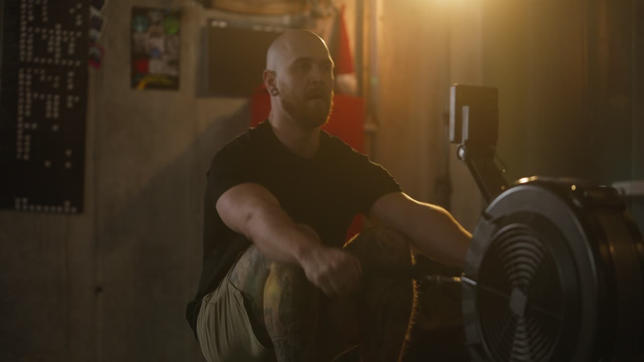 Mand, der træner på romaskine i fitnesscenter