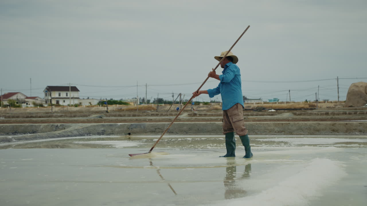 Man raking salt in a traditional salt field