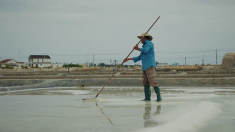 man raking salt in a traditional salt field