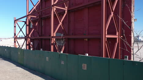 A-low-angle-shot-of-an-old-building's-red-facade-behind-a-green-wooden-fence