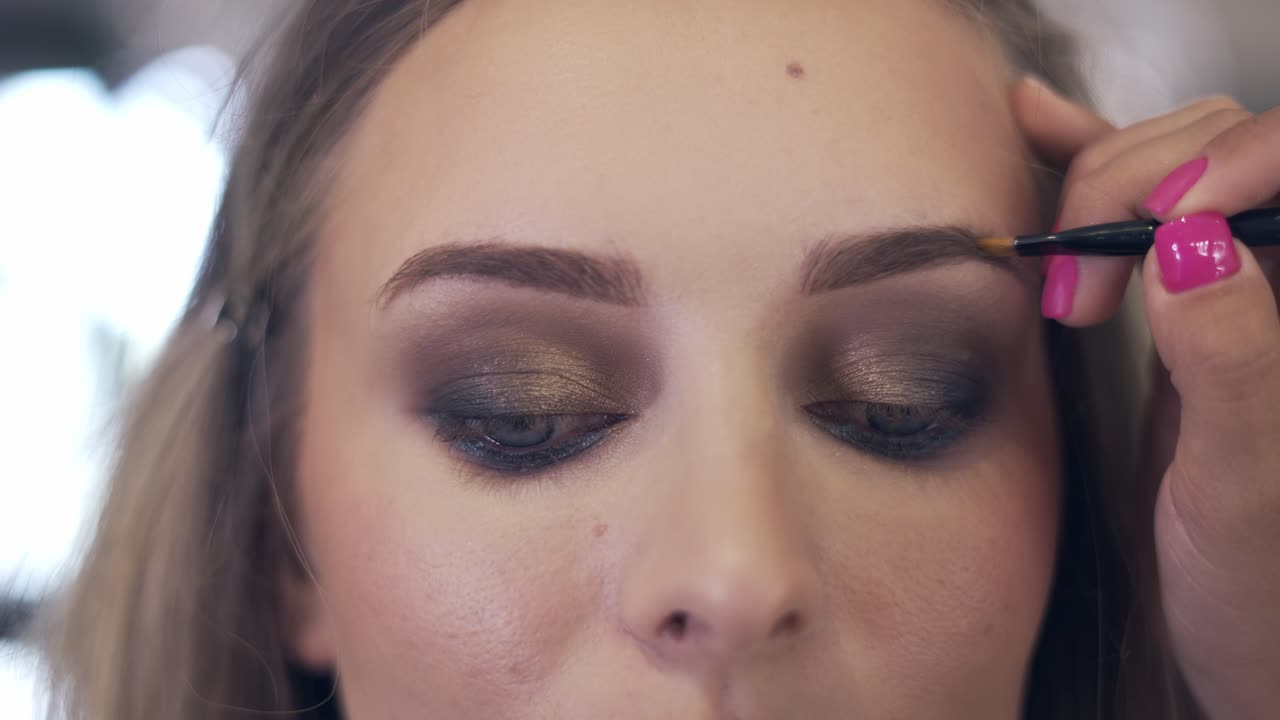 el artista de maquillaje pinta las cejas con un pincel