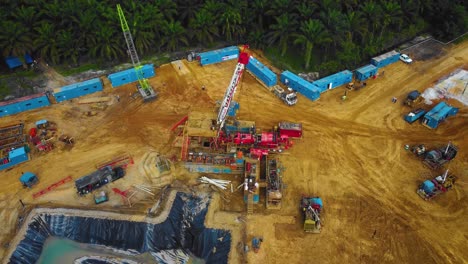 imágenes cinematográficas de drones de la estructura del equipo de la plataforma de perforación en tierra para la exploración y explotación de petróleo en medio de la jungla rodeada de palmeras durante la puesta de sol y el alto precio del petróleo