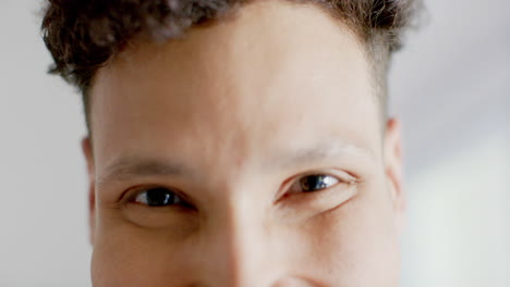 retrato de un hombre biracial feliz mirando a la cámara en casa, en cámara lenta