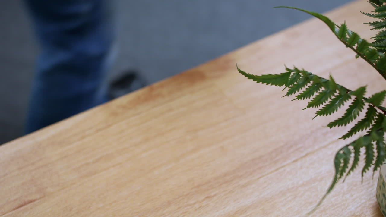 un hombre recogiendo una taza de café de un escritorio de mesa cuando sale de la oficina