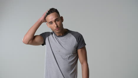 young man in t-shirt runs hand through hair, turns, waist up