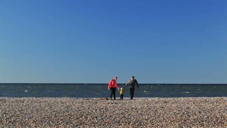 Junge-Eltern-Mit-Ihrem-Kleinen-Kind-Am-Strand