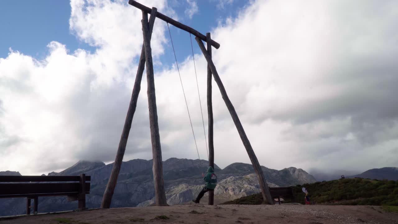 Wide shot of a female swinging in a large swing set in the nature in Asturias