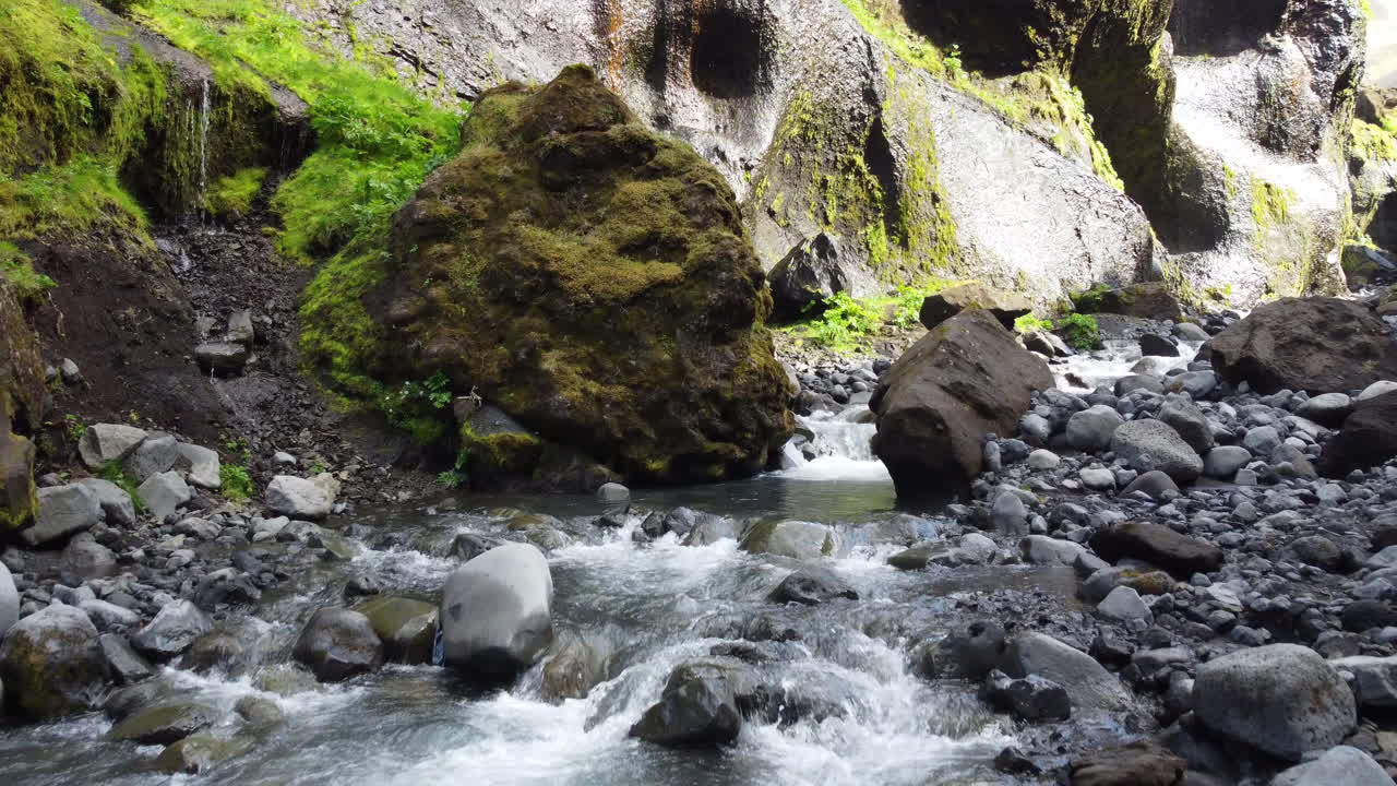 Dynamic aerial flight over the mountain river on the bottom of a rocky ravine