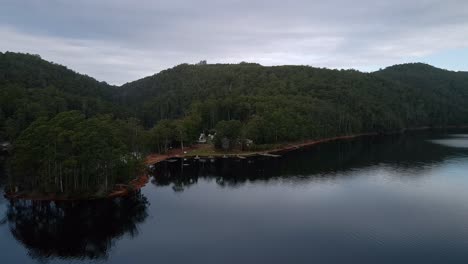 Aerial-view-of-Lake-Barrington-camp-site-on-a-calm,-cloudy-day-near-Sheffield-in-Tasmania,-Australia