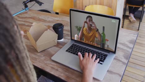 mixed race man sitting in cafe using laptop making video call with female friend