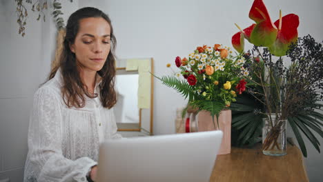 thoughtful businesswoman type computer laptop in flower store. work concept.