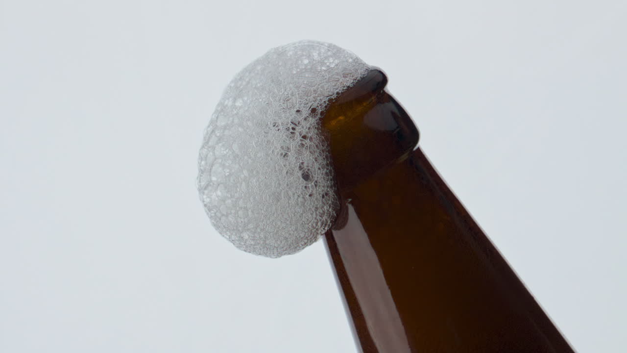 espuma de cerveja fluindo pescoço da garrafa em super câmera lenta close-up. bebida de trigo espumando