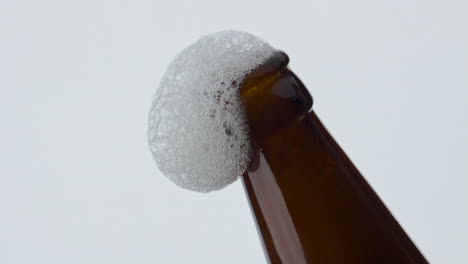 espuma de cerveza fluyendo cuello de la botella en súper cámara lenta de cerca. bebida de trigo espumando