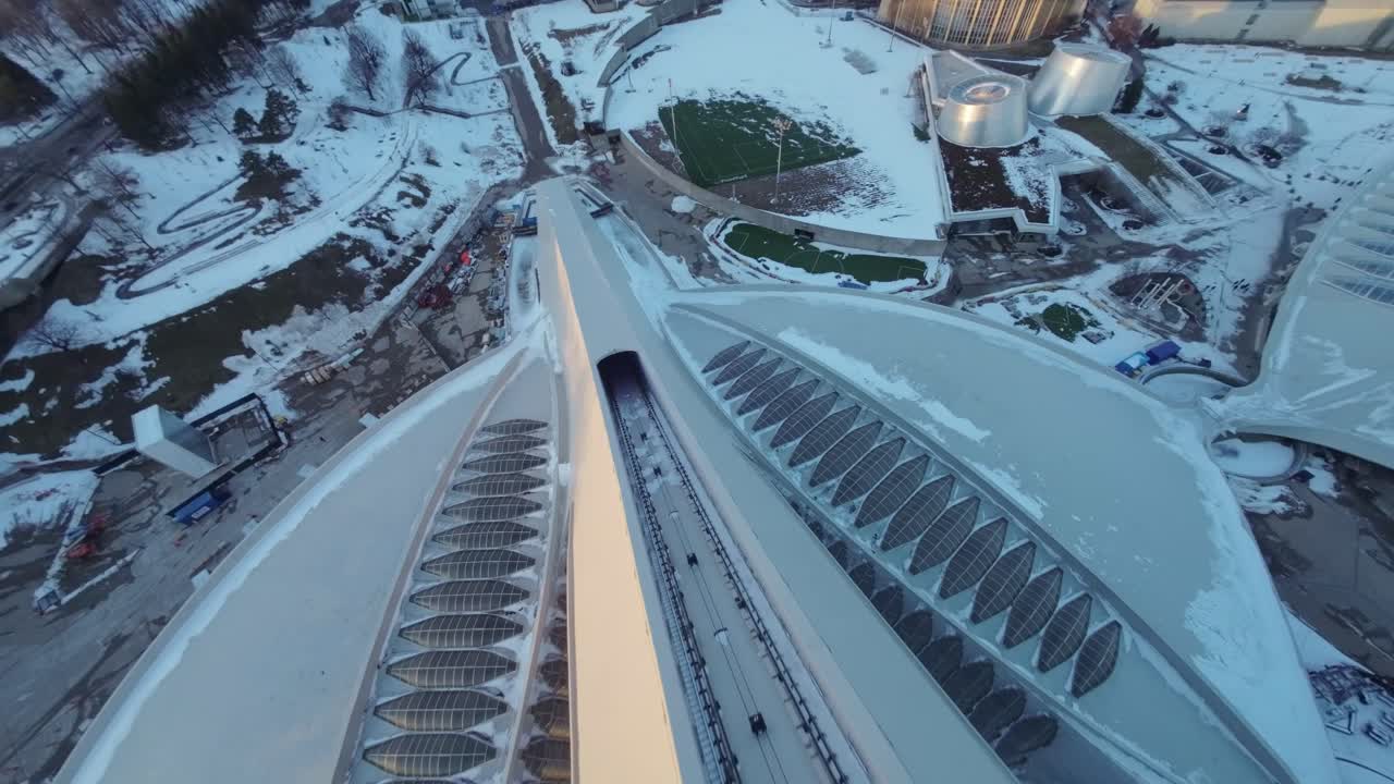 Dramatic FPV drone view over Montreal Olympic Stadium, snow-covered roof at winter sunset