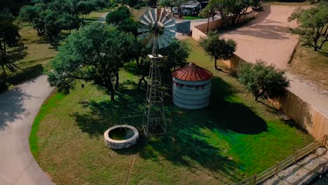 drone shot of farmland’s old rusty windmill and water well on a blue sky summer day